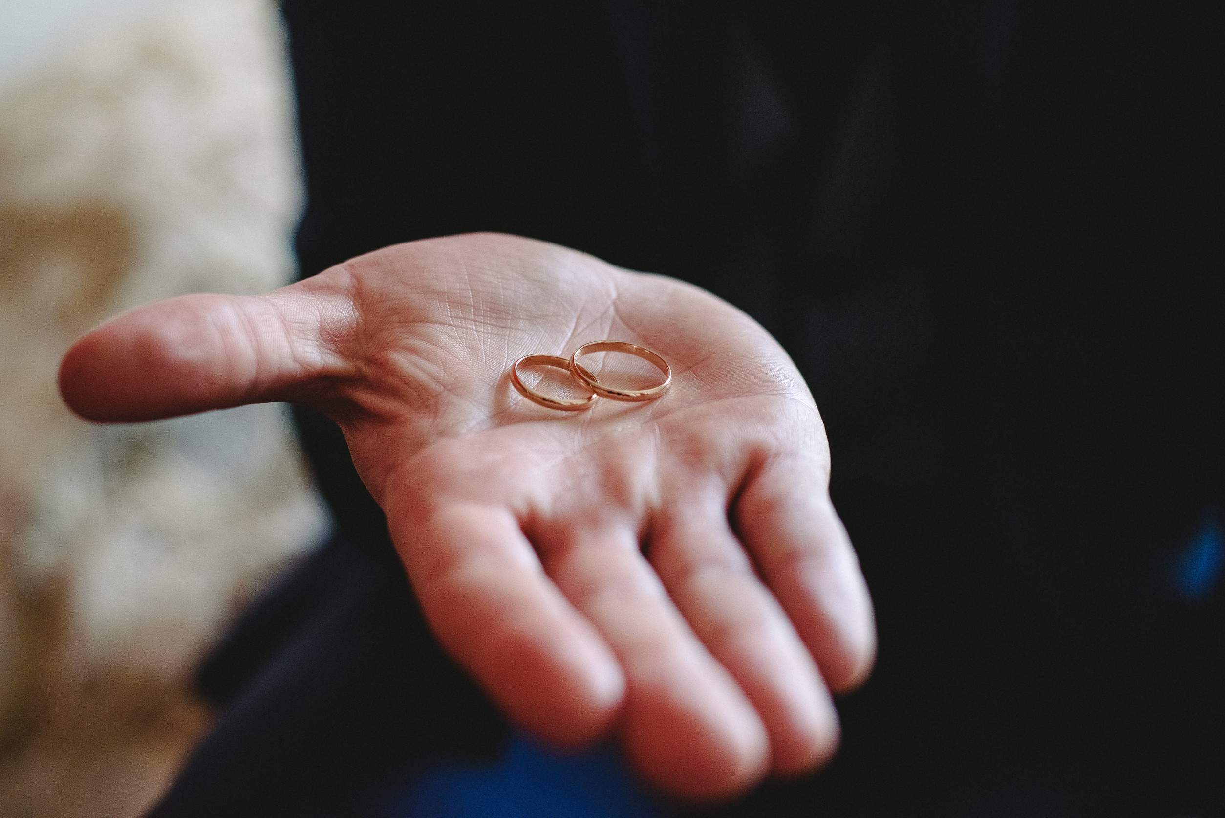 A close-up of an open hand holding two simple gold wedding rings, symbolizing the end of a union, with a blurred background—hinting at themes of divorce or legal separation.