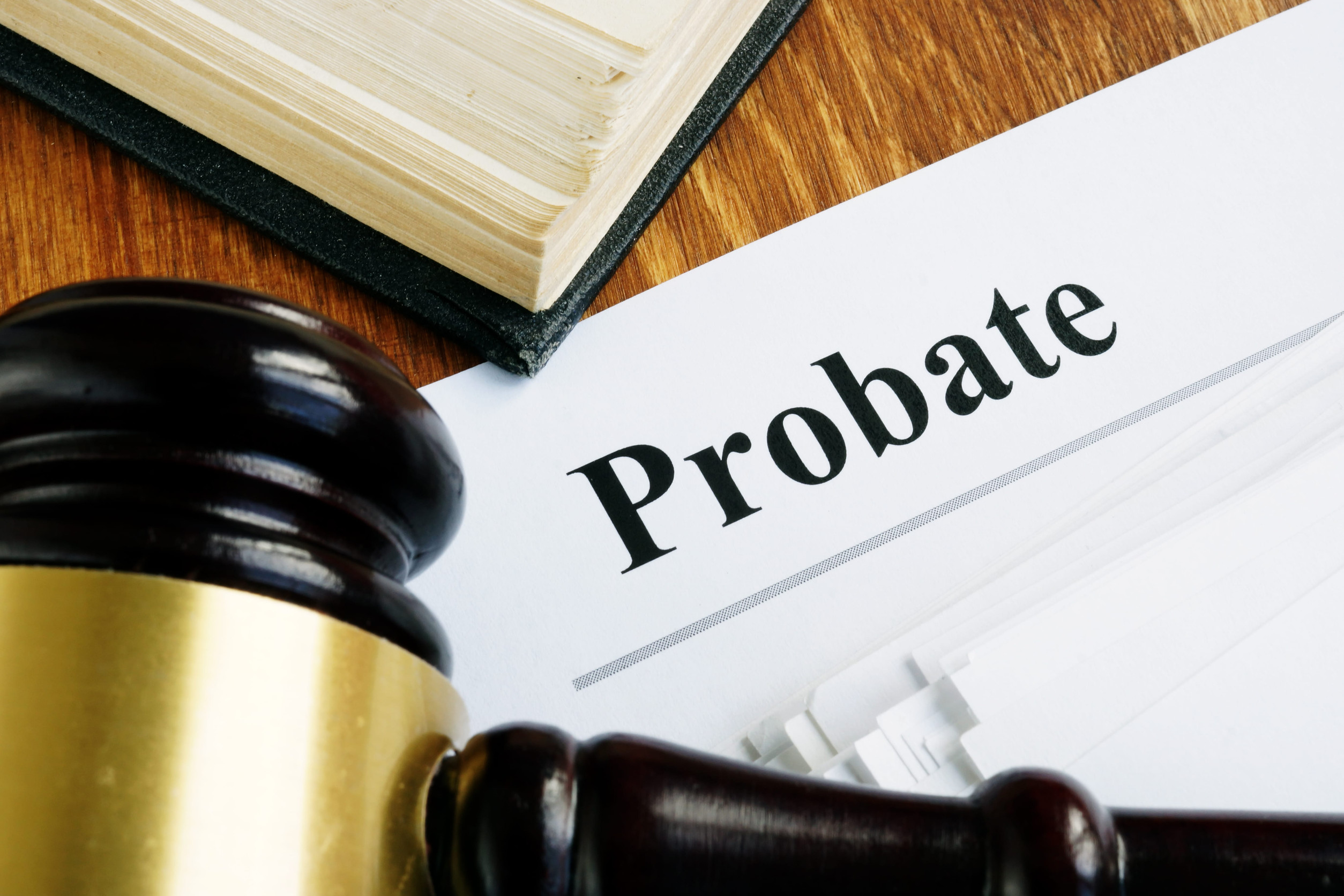Close-up of a judge's gavel beside a probate document on a wooden desk, conveying legal proceedings.